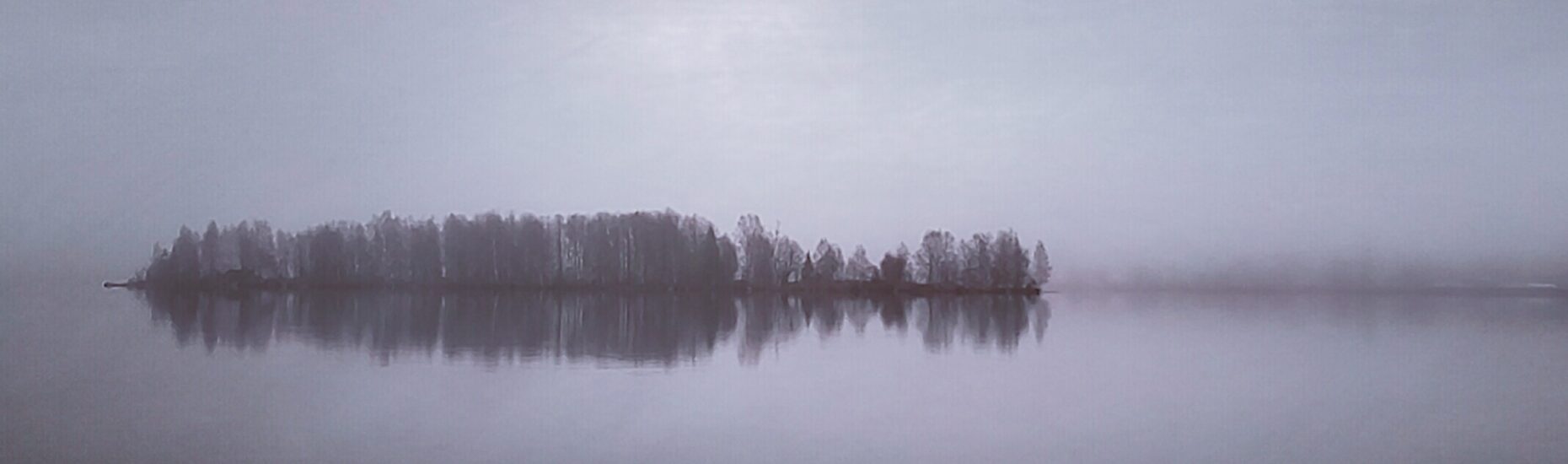 Pitkulainen saari sumuisella joella.