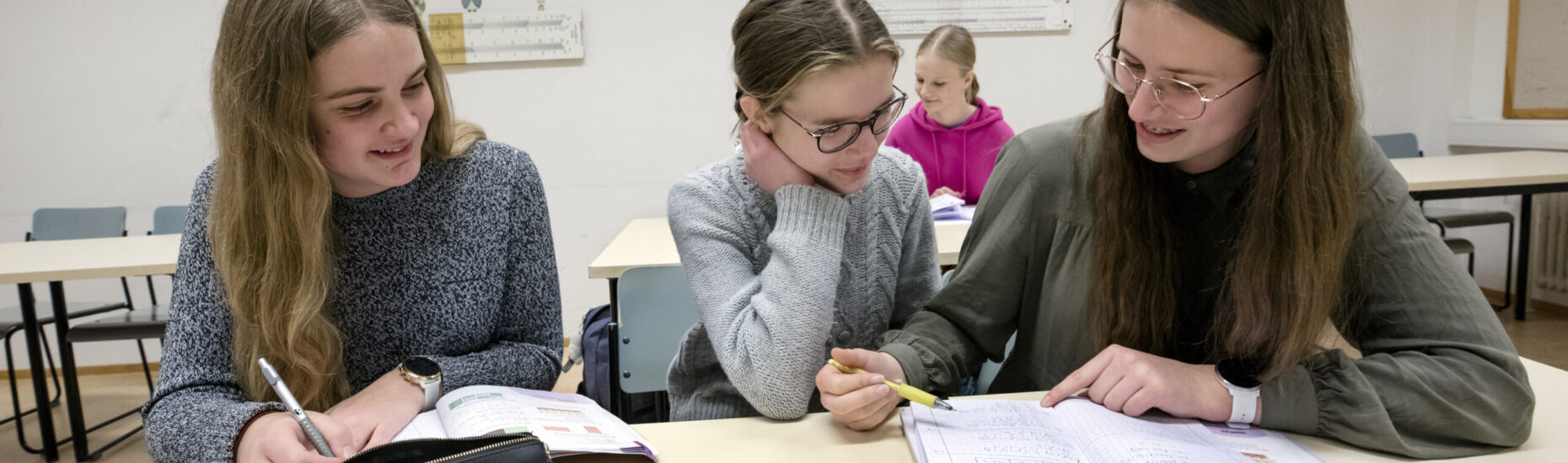 Neljä noin 15-vuotiasta tyttöä luokkahuoneessa.